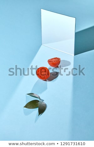 Composition Of Green Leaves Of Juicy Tomato And A Mirror On A Blue Background With Copy Space For Te Сток-фото © artjazz