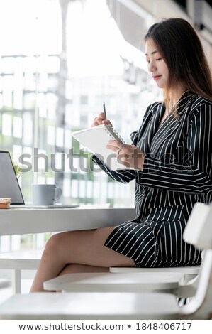 Stockfoto: Attractive Businesswoman Sits On Wooden Chair And Writes On Clip