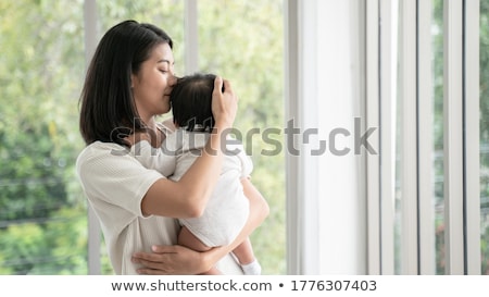 Foto d'archivio: Mom With Baby Standing At The Window
