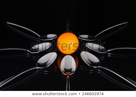 Stok fotoğraf: Teaspoons And Orange Golf Ball On The Black Glass Table