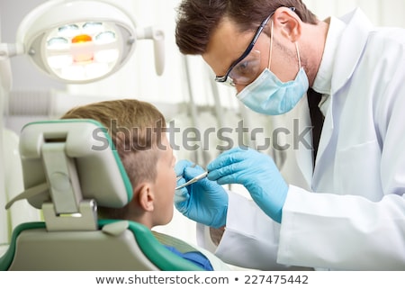 ストックフォト: Pediatric Dentist Examining A Little Boys Teeth With Assistant B