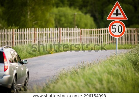 Stock fotó: Car On A Country Road With Limited Speed And Crossroad Sign