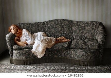 Foto stock: A Woman Lying On A Sofa In A Red Dress