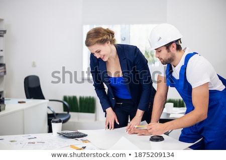 Stok fotoğraf: Male And Female Workers With Technical Blueprints Talking At Con