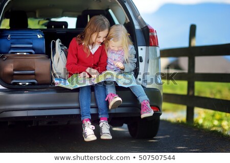 ストックフォト: Tourist Sitting On The Suitcase And Looks Map