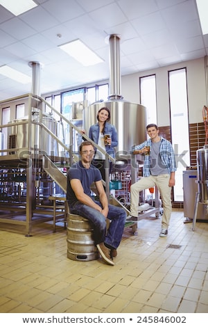 Stock photo: Man Siting On Keg And His Colleague Holding A Glass Of Beer