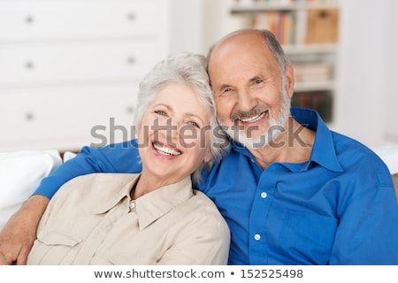 Foto d'archivio: Affectionate Attractive Elderly Couple Sitting Together On A Couch With Tablet