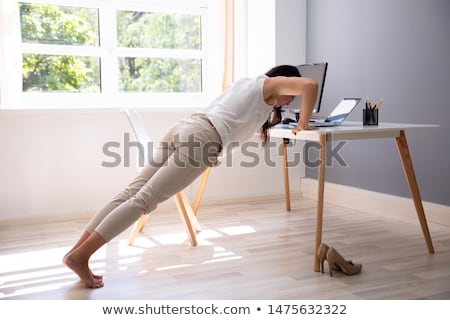 Zdjęcia stock: Businesswoman Doing Push Up On Office Desk