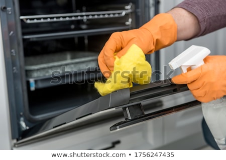 Foto stock: Janitor Cleaning Oven In The Kitchen