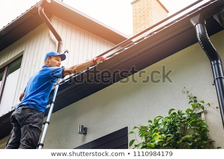 Stock photo: Man On A Ladder Cleaning House Gutters