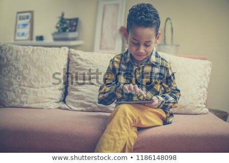 Foto d'archivio: Front View Of African American Boy Playing Game On Digital Tablet At Dining Table In Kitchen At Home