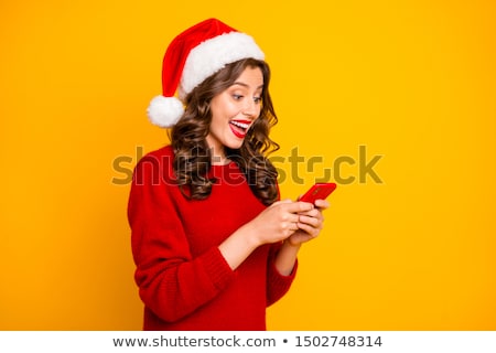 Stock photo: Pretty Woman In A Santa Hat Reading An Sms