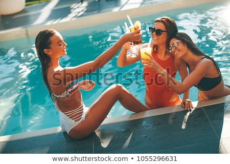 Foto stock: Young Women Drinking Coctail And Having Fun By The Swimming Pool