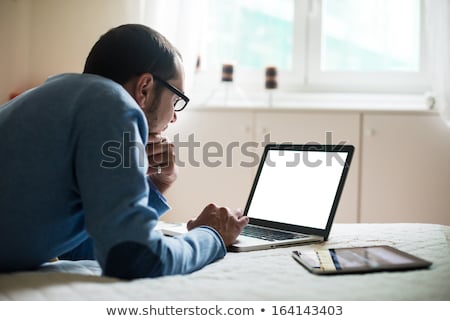 Stockfoto: Young Man Using A Tablet In Bed