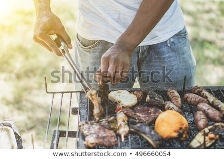 Zdjęcia stock: Young Man Cooking Sausages On Barbecue During Summer