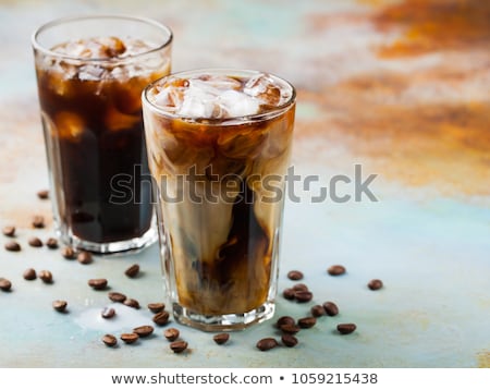 Foto stock: Ice Coffee In A Tall Glass With Cream Poured Over And Coffee Beans