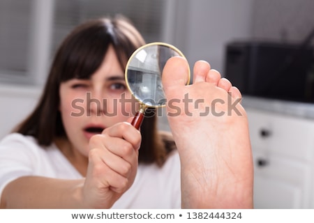 Stockfoto: Woman Looking At Her Toe Nails With Magnifying Glass