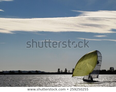 Сток-фото: A Small Dinghy With Large Yellow Sail Under A Blue Sky Sailing O