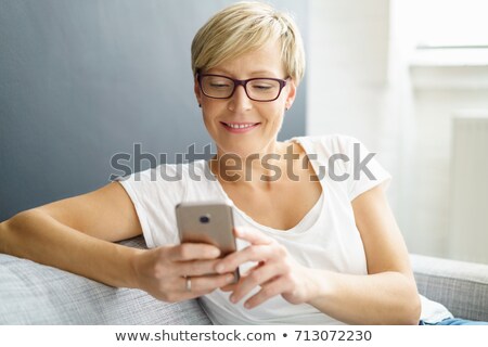 Stock fotó: Young Casual Blonde Woman Reading Messages On Her Phone