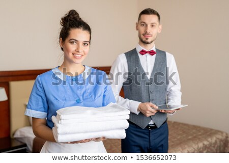 [[stock_photo]]: Pretty Young Smiling Chamber Maid Standing In Front Of Camera With Porter Behind