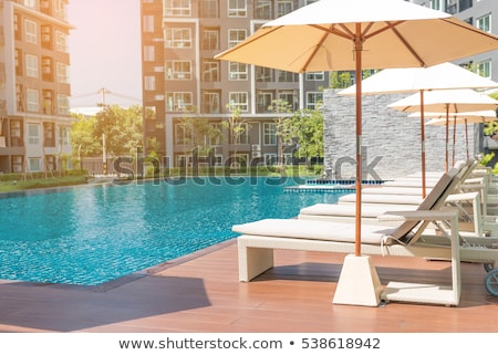 Foto stock: Seat And Chairs On Deck By Swimming Pool