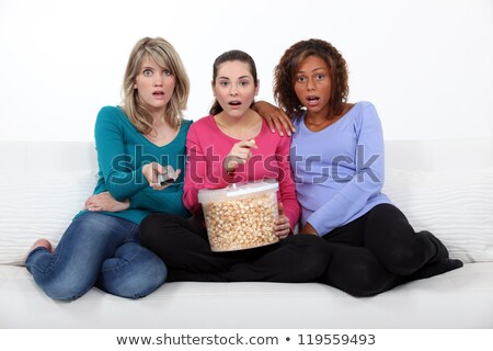 Stock fotó: Three Scared Women Sat On Sofa Watching Movie