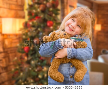 Foto d'archivio: Young Girl Standing With Teddy Bear In Front Of Christmas Tree