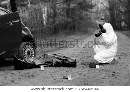Foto stock: Criminalist Photographing Dead Body At Crime Scene