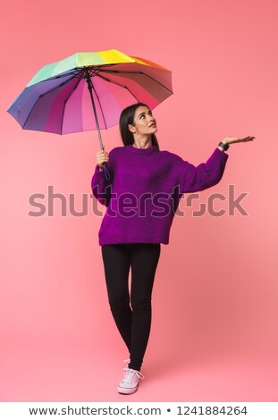 Foto d'archivio: Emotional Young Woman Posing Isolated Over Pink Background Holding Rainbow Umbrella