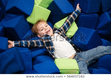 Stok fotoğraf: Cheerful Little Boy Lying In Pool With Soft Cube Pillows