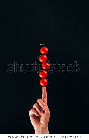 Zdjęcia stock: Cropped Shot Of Woman Holding Cherry Tomatoes On Finger Isolated On Black