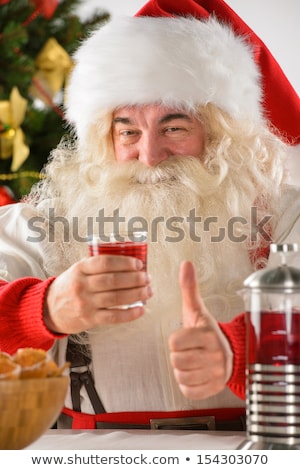 Foto stock: Santa Claus At Home Eating Cookies And Drinking Red Tea