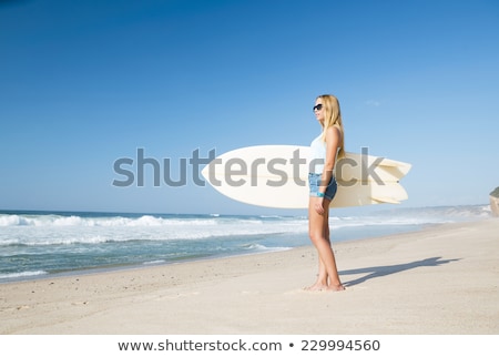 Foto stock: Beautiful Surfer Girl Walking From The Sea With Her Surfboard