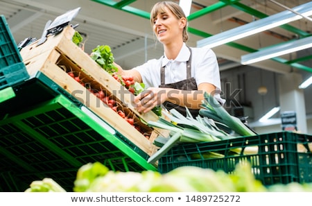 Foto stock: Woman Working In A Supermarket Sorting Fruit And Vegetables