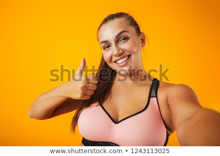 Foto stock: Portrait Of Joyful Chubby Woman In Sportive Bra Using Mobile Pho