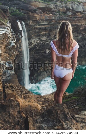 Foto stock: Woman Stands By A Roaring Waterfall Tumbling Into The Ocean
