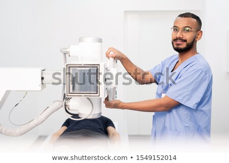 Foto d'archivio: Successful Young Doctor In Blue Uniform And Eyeglasses Using New Equipment