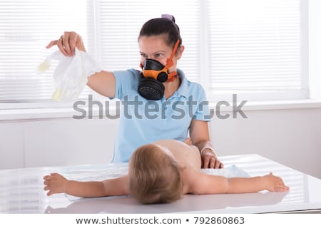 Foto stock: Mother Changing Her Babys Diaper With Gas Mask