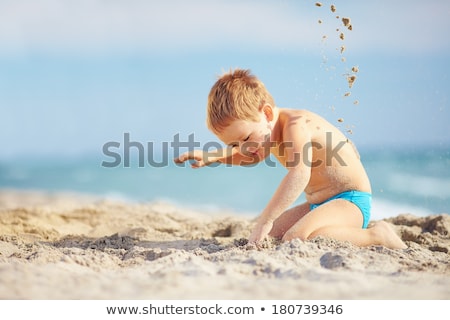 Foto stock: Happy Young Boy Is Digging In The Sand Of The Beach