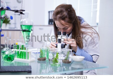 Foto stock: Female Biologist Adjusting Microscope