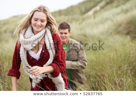 Stock photo: Young Couple Walking Through Sand Dunes Wearing Warm Clothing