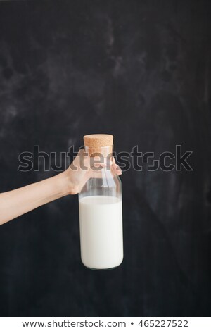 Stock fotó: Woman Hand Keeps The Bottle With Milk On Black Background