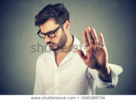 Foto d'archivio: Annoyed Sad Man Giving Talk To Hand Gesture Isolated On Gray Background