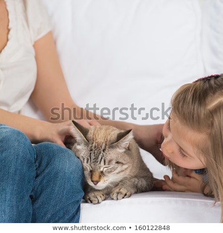 Foto d'archivio: A Happy Family Of Two With A Cat Sitting On Sofa And Having Fun