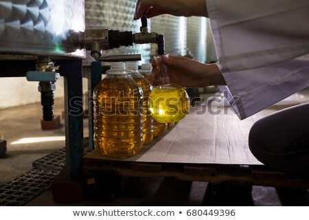 ストックフォト: Mid Section Of Female Technician Examining Olive Oil