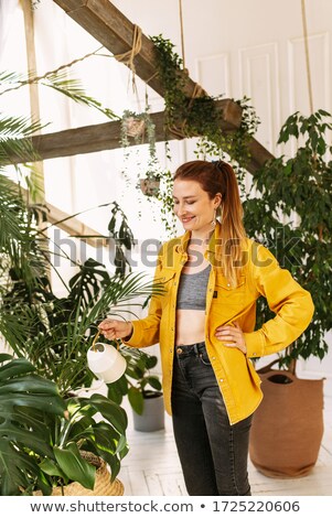 Foto d'archivio: Young Woman Watering Plants In Her Garden