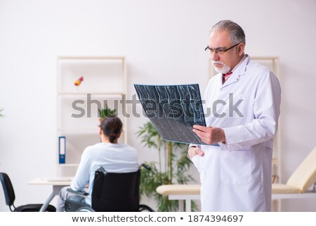 Foto d'archivio: Young Man With Broken Leg Sitting On Wheelchair And Looking At Radiologist