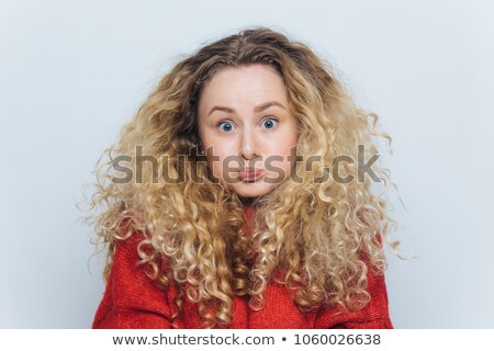 Stockfoto: Fuuny Blonde Female With Curly Hair Blows Cheeks And Stares At Camera Reacts Actively On Unexpecte