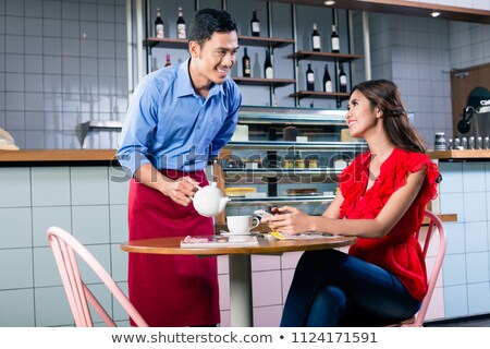 Stok fotoğraf: Handsome Waiter Flirting With A Beautiful Woman While Serving Coffee