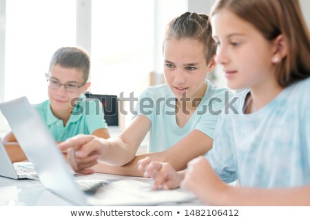 Clever Boy Pointing At Laptop Display While Showing Something To Girl Foto stock © Pressmaster